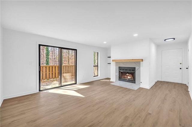 unfurnished living room featuring a premium fireplace and light hardwood / wood-style flooring