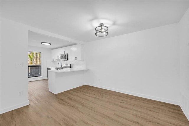 bar with white cabinetry, appliances with stainless steel finishes, backsplash, and light wood-type flooring