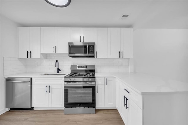 kitchen featuring white cabinetry, stainless steel appliances, sink, and light wood-type flooring