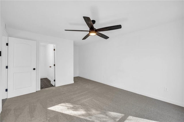 spare room with ceiling fan and dark carpet