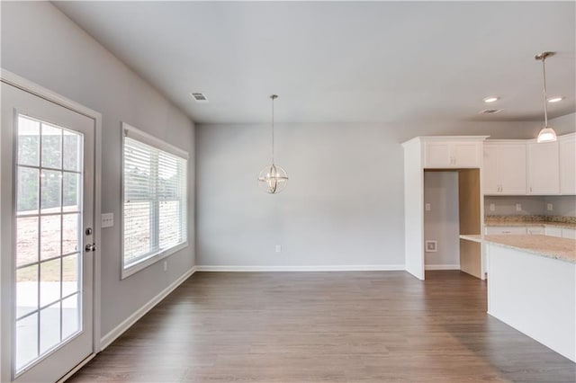 interior space with light stone countertops, pendant lighting, white cabinetry, and dark wood-type flooring