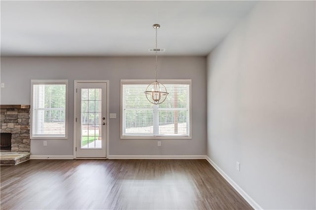 doorway to outside featuring plenty of natural light, wood-type flooring, a fireplace, and an inviting chandelier