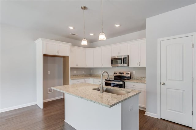 kitchen with light stone countertops, appliances with stainless steel finishes, a center island with sink, white cabinets, and hanging light fixtures