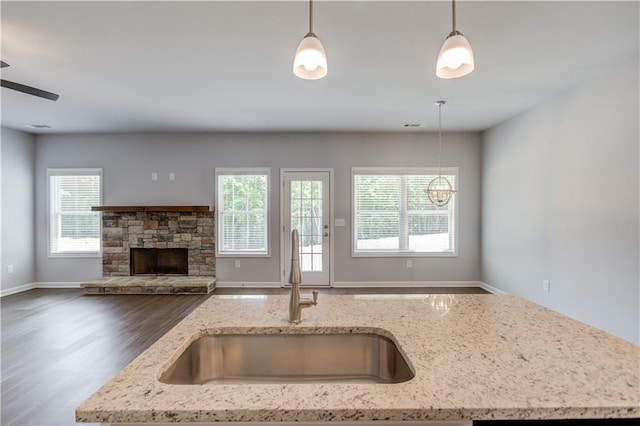 kitchen featuring pendant lighting, light stone countertops, and sink