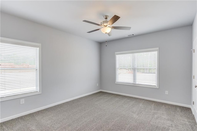 carpeted empty room featuring a wealth of natural light and ceiling fan