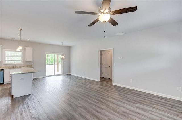 unfurnished living room with hardwood / wood-style floors, ceiling fan with notable chandelier, and sink