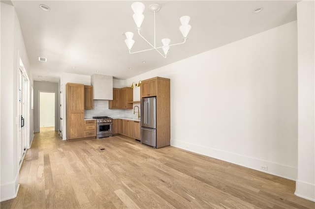 kitchen with tasteful backsplash, a notable chandelier, light hardwood / wood-style floors, decorative light fixtures, and appliances with stainless steel finishes