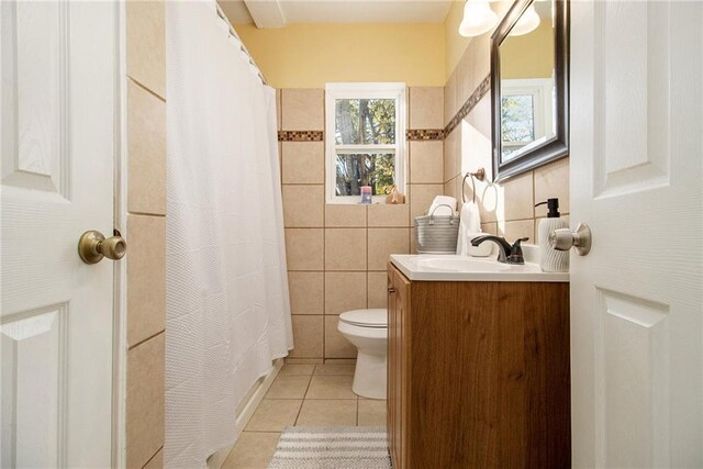 bathroom with tile patterned flooring, vanity, toilet, and tile walls