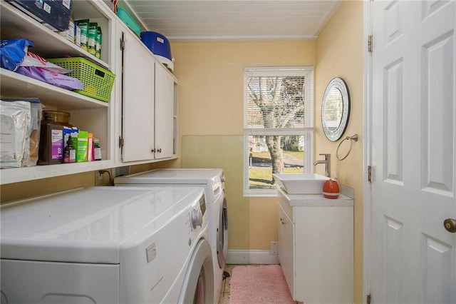 laundry area with washing machine and clothes dryer, crown molding, sink, and cabinets