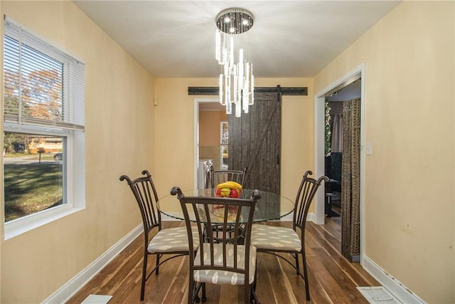 dining room featuring a barn door, dark hardwood / wood-style flooring, and a chandelier