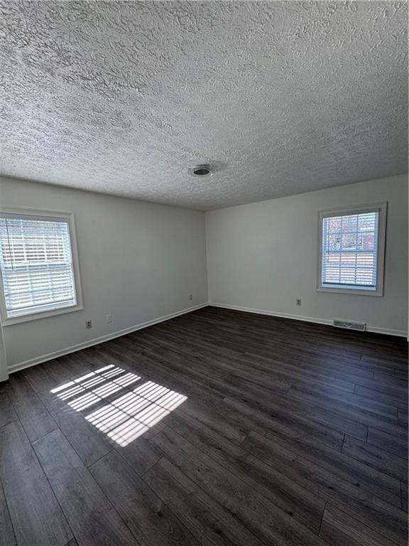 unfurnished room featuring dark hardwood / wood-style flooring, plenty of natural light, and a textured ceiling