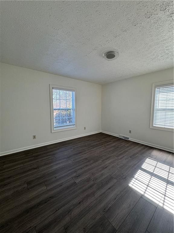 empty room featuring dark hardwood / wood-style floors and a textured ceiling