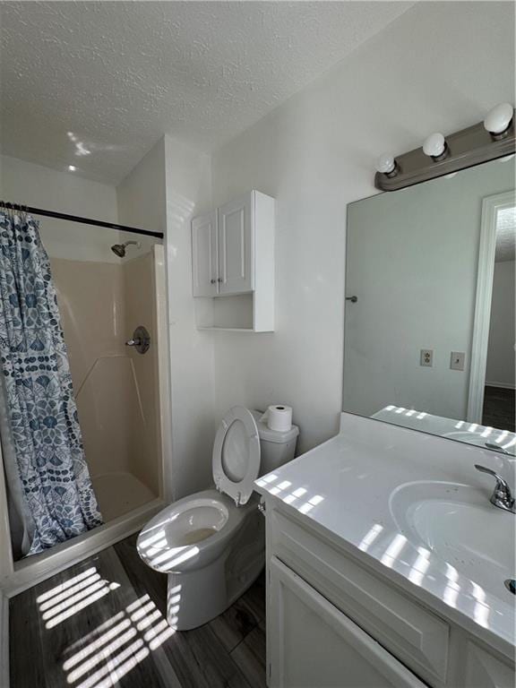 bathroom with wood-type flooring, vanity, toilet, a textured ceiling, and a shower with curtain