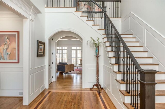 interior space featuring wood finished floors, arched walkways, a decorative wall, and stairway