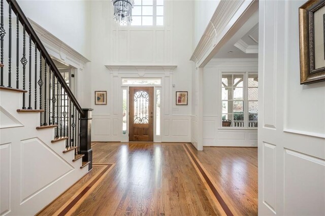 entryway featuring plenty of natural light, a towering ceiling, a decorative wall, and wood finished floors