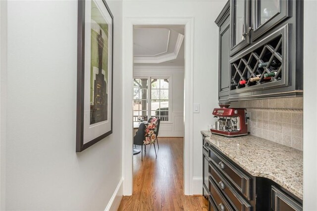 bar featuring light wood-style floors, ornamental molding, and tasteful backsplash