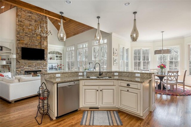 kitchen featuring dishwasher, a sink, lofted ceiling with beams, light wood finished floors, and open floor plan