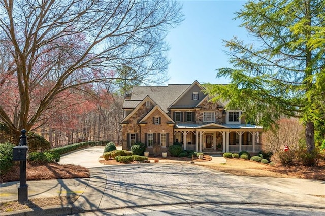 craftsman-style house featuring concrete driveway, a porch, and stone siding