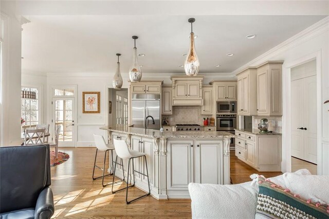 kitchen with decorative backsplash, built in appliances, cream cabinets, and ornamental molding