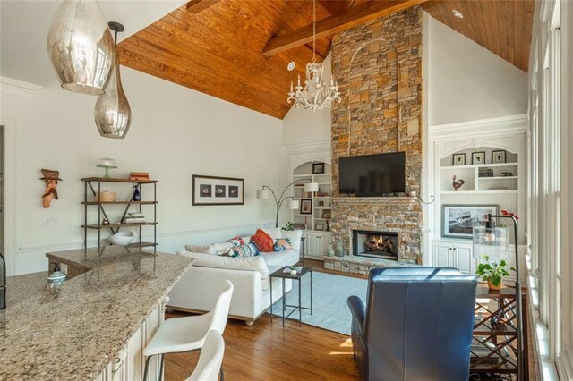 living room with wood ceiling, dark wood-style flooring, a stone fireplace, high vaulted ceiling, and a chandelier