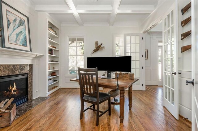 dining room with crown molding, built in shelves, beamed ceiling, and wood finished floors