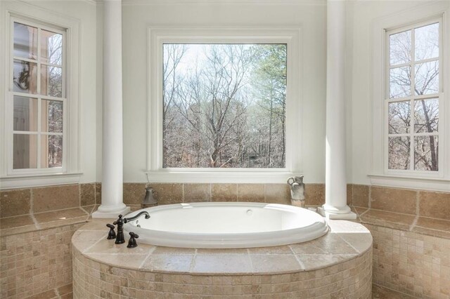 bathroom featuring a healthy amount of sunlight, decorative columns, and a bath