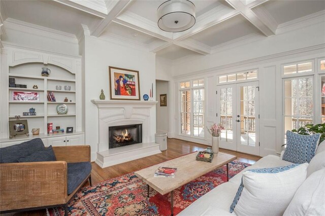 living room featuring wood finished floors, beamed ceiling, a lit fireplace, french doors, and coffered ceiling