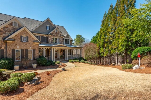 craftsman-style house featuring covered porch, brick siding, and stone siding