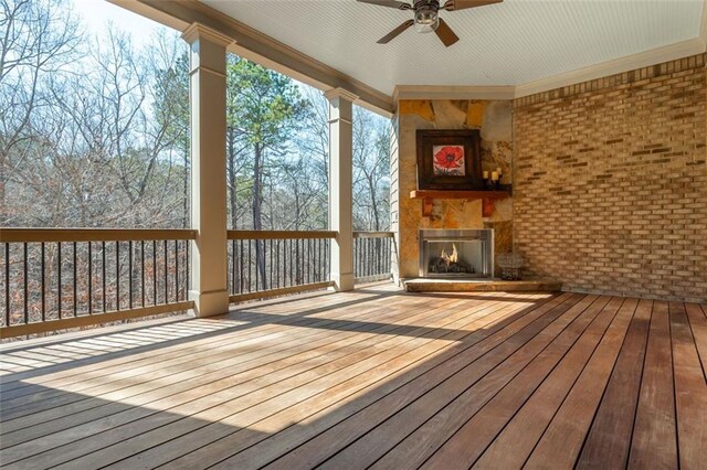 wooden terrace featuring a ceiling fan and a fireplace