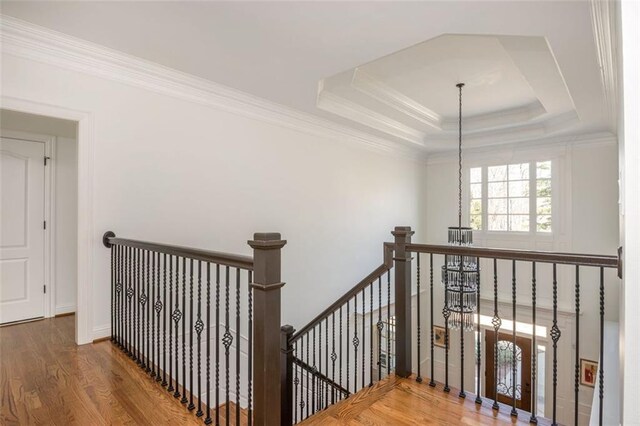 stairs with an inviting chandelier, ornamental molding, and wood finished floors