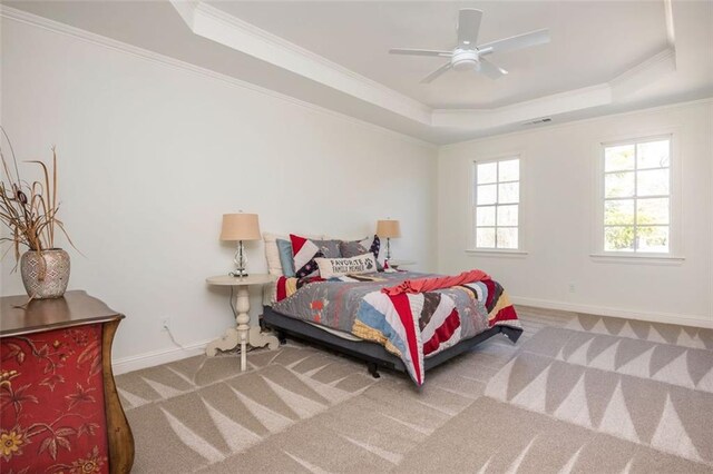 carpeted bedroom with crown molding, baseboards, a tray ceiling, and visible vents