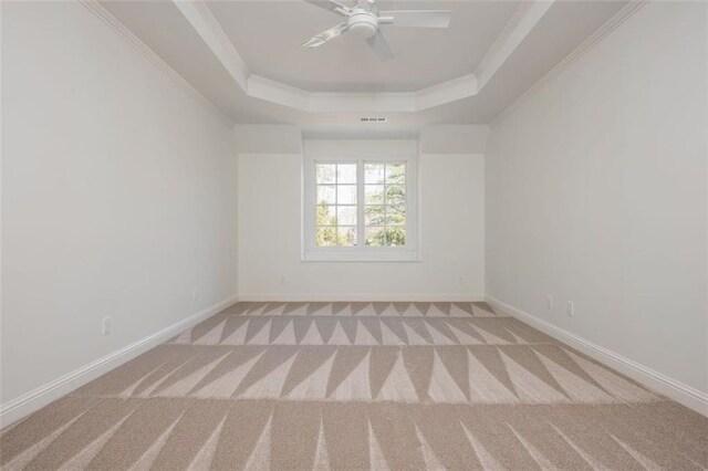 unfurnished room featuring crown molding, a raised ceiling, carpet floors, a ceiling fan, and baseboards