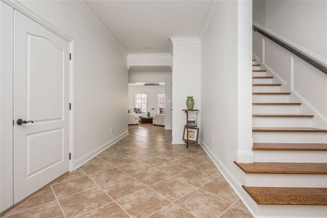 foyer entrance with crown molding, light tile patterned floors, and stairway