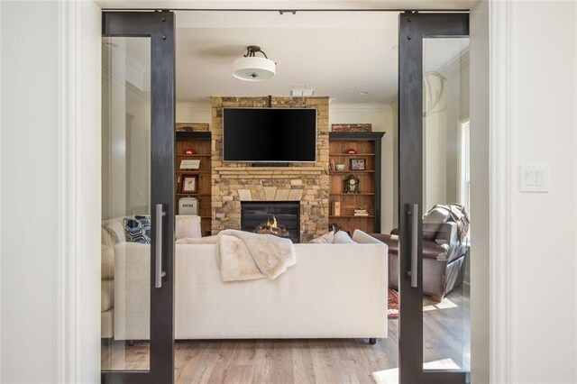 living area with ornamental molding, wood finished floors, and a fireplace