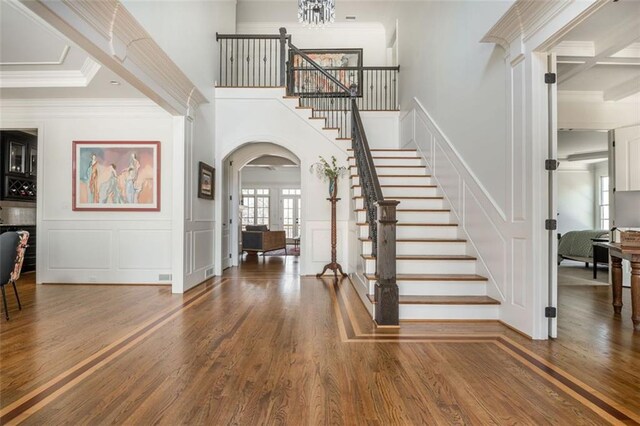foyer entrance featuring arched walkways, wood finished floors, stairway, and a decorative wall