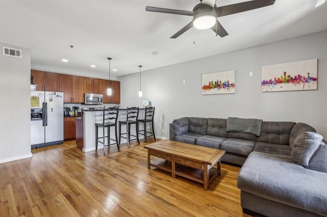 living room with ceiling fan and light hardwood / wood-style flooring