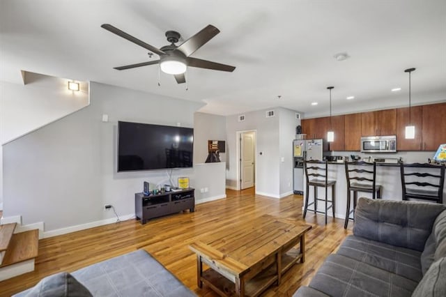 living room with ceiling fan and light hardwood / wood-style flooring