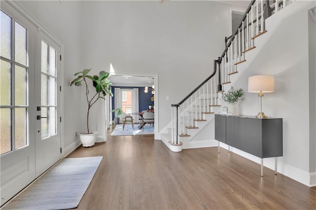 entryway with a towering ceiling, stairs, baseboards, and wood finished floors