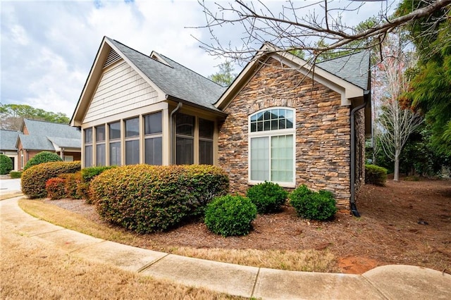 120 Chastain Rd NW Unit 1204, Kennesaw, GA 30144 - view of side of home featuring a chimney, a shingled roof, a sunroom, and stone siding