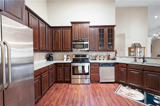 120 Chastain Rd NW Unit 1204, Kennesaw, GA 30144 - kitchen featuring tasteful backsplash, stainless steel appliances, a sink, a towering ceiling, and wood finished floors