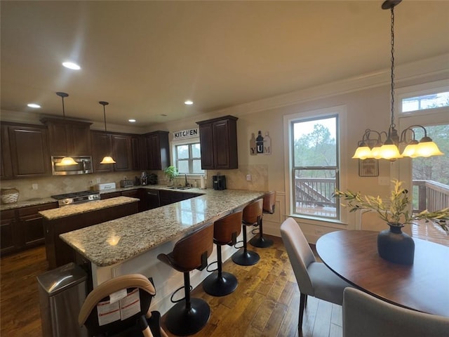 kitchen featuring a sink, stainless steel microwave, tasteful backsplash, and dark brown cabinets