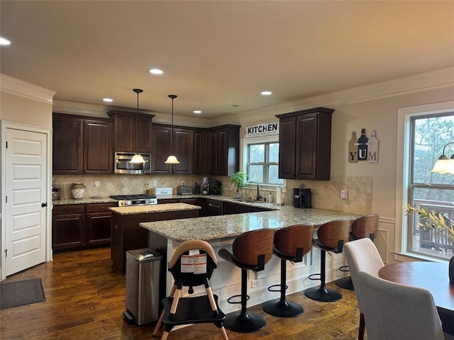 kitchen with stainless steel microwave, dark brown cabinets, a peninsula, and dark wood-style flooring