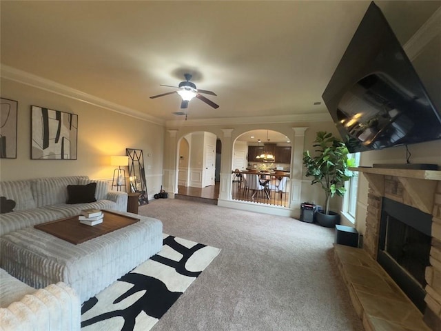 carpeted living room with arched walkways, a fireplace, crown molding, and ceiling fan