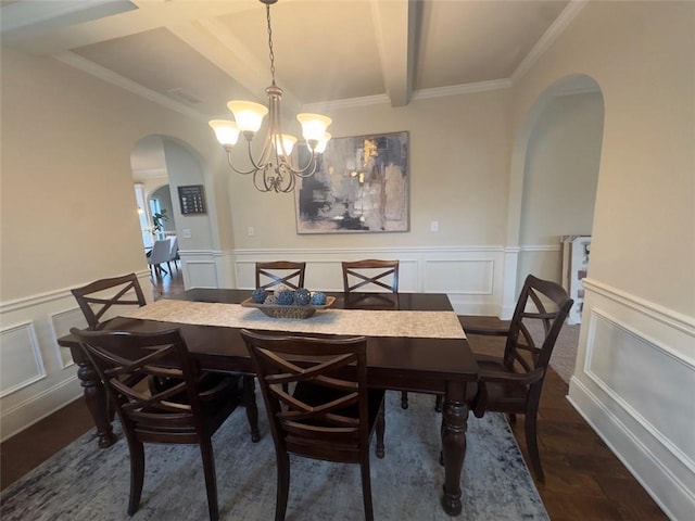 dining area with arched walkways, beam ceiling, wainscoting, and a decorative wall