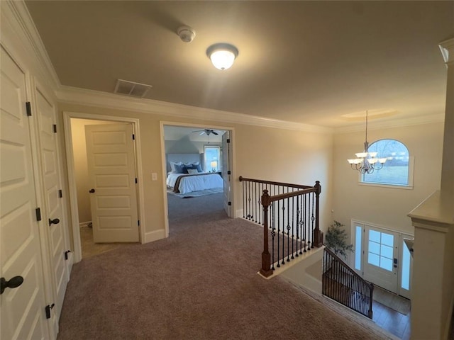 hall featuring visible vents, carpet, ornamental molding, an upstairs landing, and a notable chandelier