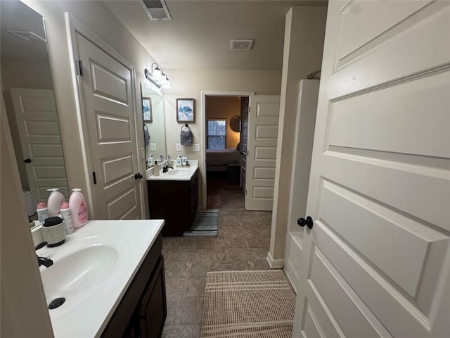 ensuite bathroom featuring visible vents, two vanities, a sink, connected bathroom, and walk in shower