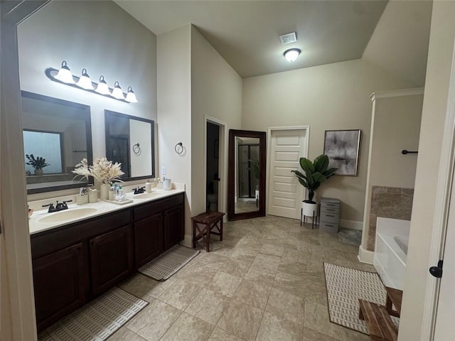 full bathroom with a bath, double vanity, baseboards, and a sink