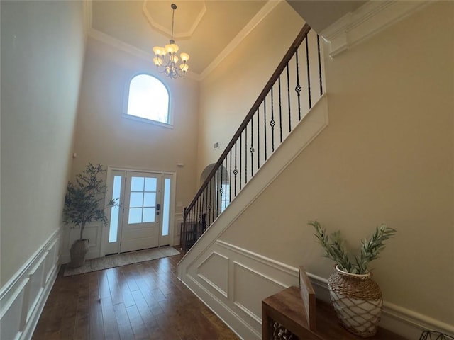 entrance foyer with an inviting chandelier, wood finished floors, crown molding, and a decorative wall