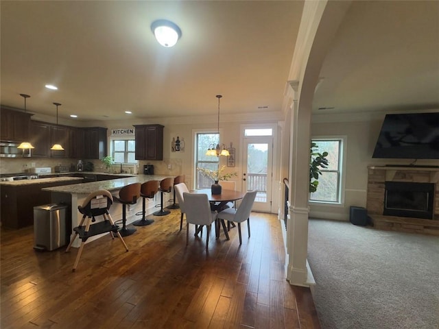 dining room featuring dark wood finished floors, a fireplace, an inviting chandelier, and ornamental molding