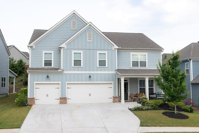 view of front of property with a porch, a garage, and a front lawn